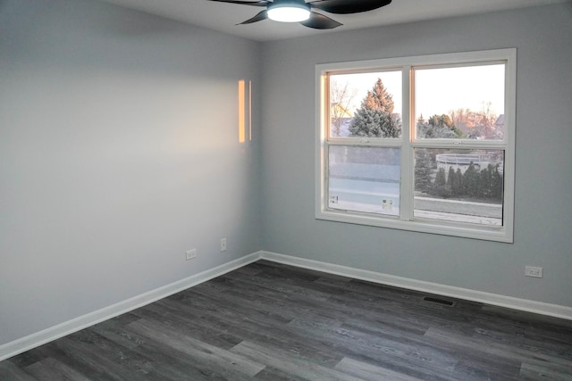 spare room featuring dark wood-style floors, ceiling fan, visible vents, and baseboards