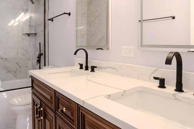 bathroom featuring double vanity, shower / bath combination, toilet, and a sink