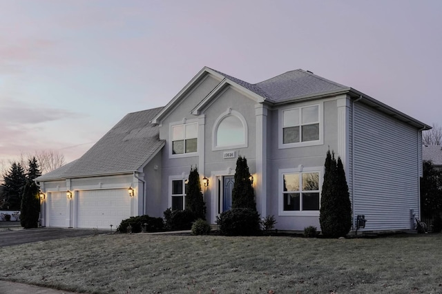 view of front of house with aphalt driveway, an attached garage, a yard, roof with shingles, and stucco siding