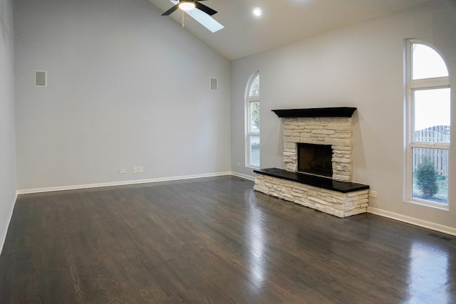 unfurnished living room featuring dark wood-style floors, a wealth of natural light, visible vents, and a stone fireplace