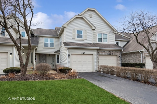 view of front of home with an attached garage, a front lawn, aphalt driveway, and brick siding