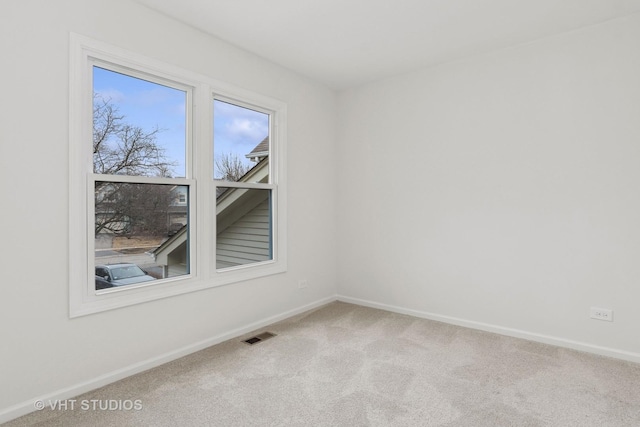 carpeted spare room with visible vents and baseboards