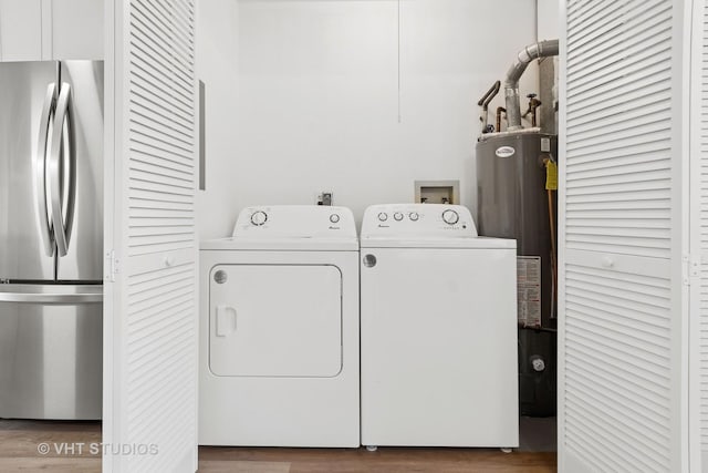 clothes washing area with gas water heater, independent washer and dryer, and wood finished floors