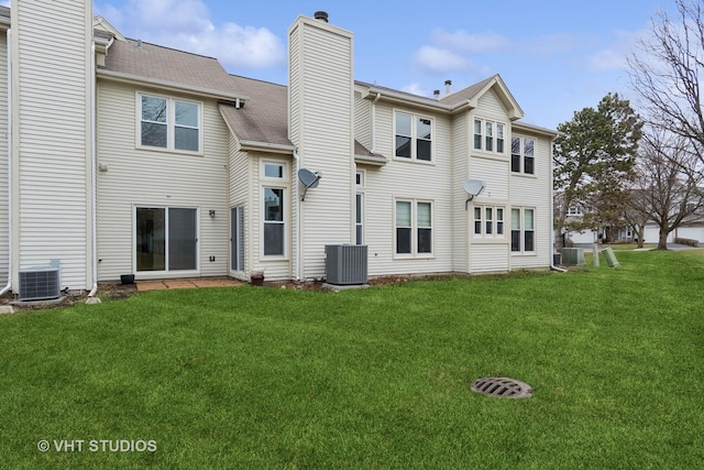 back of property featuring central AC, a lawn, and a chimney