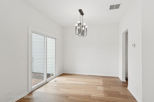 spare room with light wood-type flooring, visible vents, baseboards, and an inviting chandelier