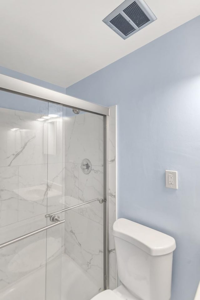 bathroom featuring toilet, a marble finish shower, and visible vents