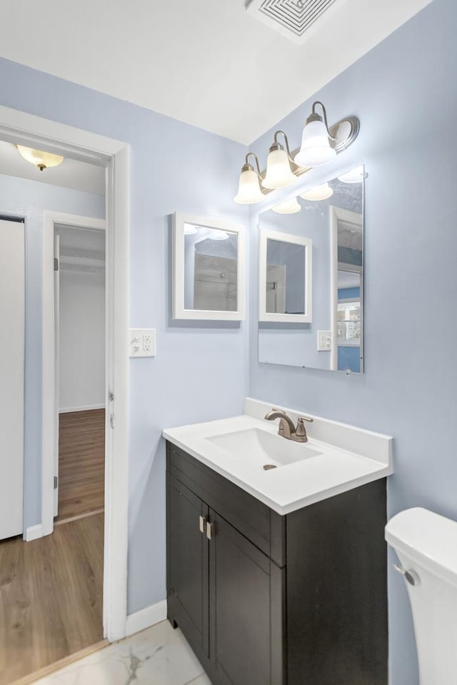 bathroom with toilet, vanity, visible vents, and baseboards