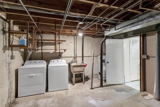 unfinished below grade area featuring water heater, separate washer and dryer, and a sink