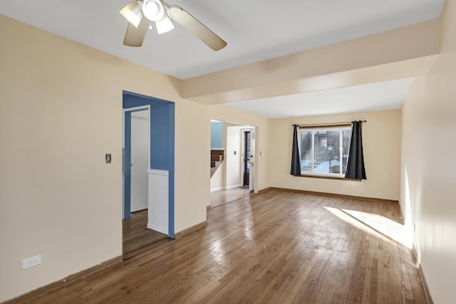 unfurnished room with a ceiling fan, stairs, baseboards, and wood finished floors