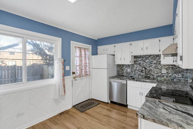 kitchen with white cabinets, dishwasher, freestanding refrigerator, range hood, and a sink