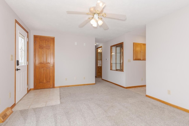 spare room featuring a ceiling fan, light colored carpet, visible vents, and baseboards