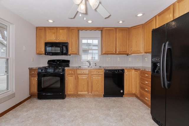 kitchen with decorative backsplash, baseboards, a sink, and black appliances