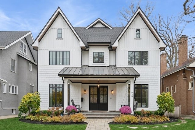 modern farmhouse style home with metal roof, covered porch, french doors, roof with shingles, and a standing seam roof