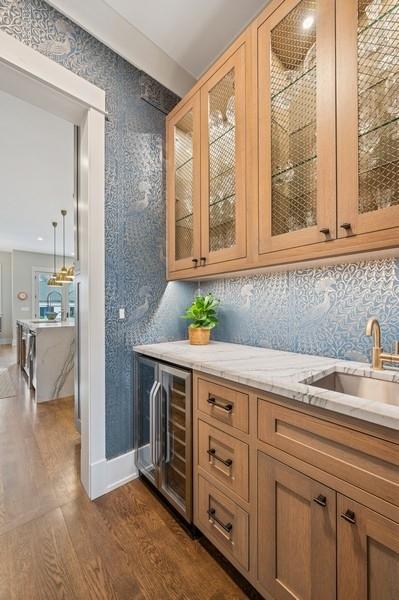 bar with beverage cooler, baseboards, dark wood-style floors, a sink, and backsplash