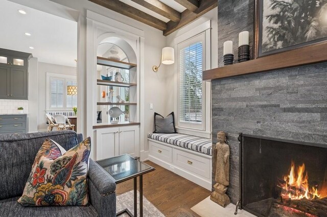 living area with recessed lighting, dark wood-style flooring, beamed ceiling, and a lit fireplace