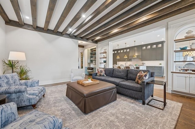 living area with recessed lighting, beam ceiling, baseboards, and wood finished floors