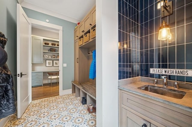 mudroom featuring tile patterned flooring, tile walls, a sink, and built in study area