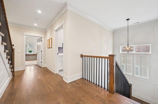 corridor featuring an upstairs landing, crown molding, baseboards, and wood finished floors