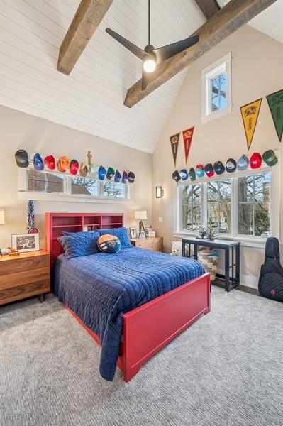 carpeted bedroom featuring high vaulted ceiling, beamed ceiling, and a ceiling fan