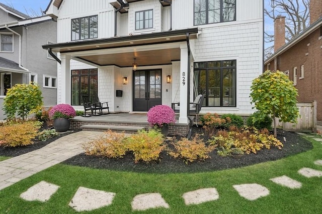 back of house featuring a porch, board and batten siding, and french doors