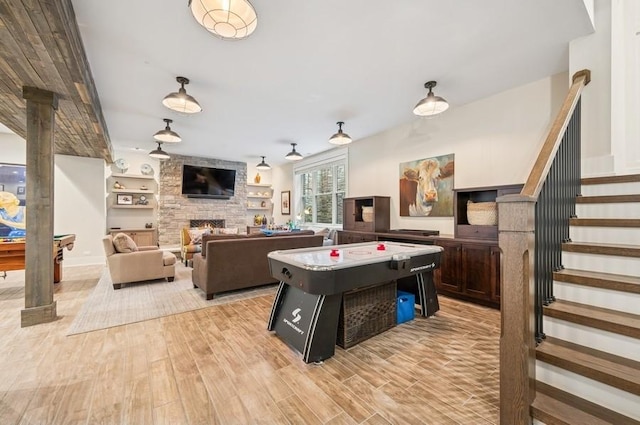 rec room featuring built in shelves, a fireplace, and light wood-style flooring