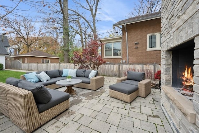 view of patio with an outdoor living space with a fireplace and fence