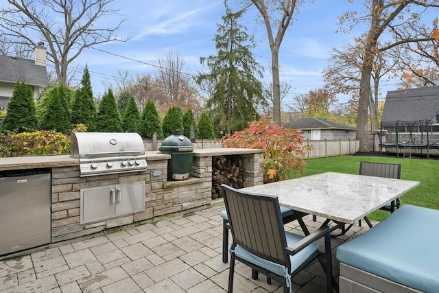 view of patio with area for grilling, fence private yard, a trampoline, outdoor dining area, and exterior kitchen