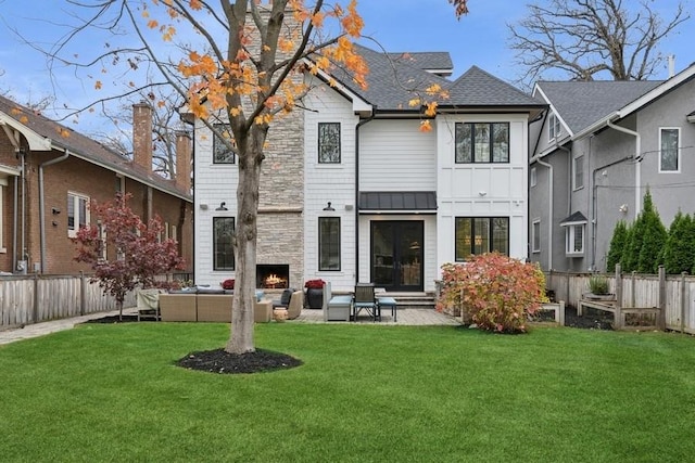 back of property featuring a patio, a shingled roof, a lawn, an outdoor living space with a fireplace, and fence private yard