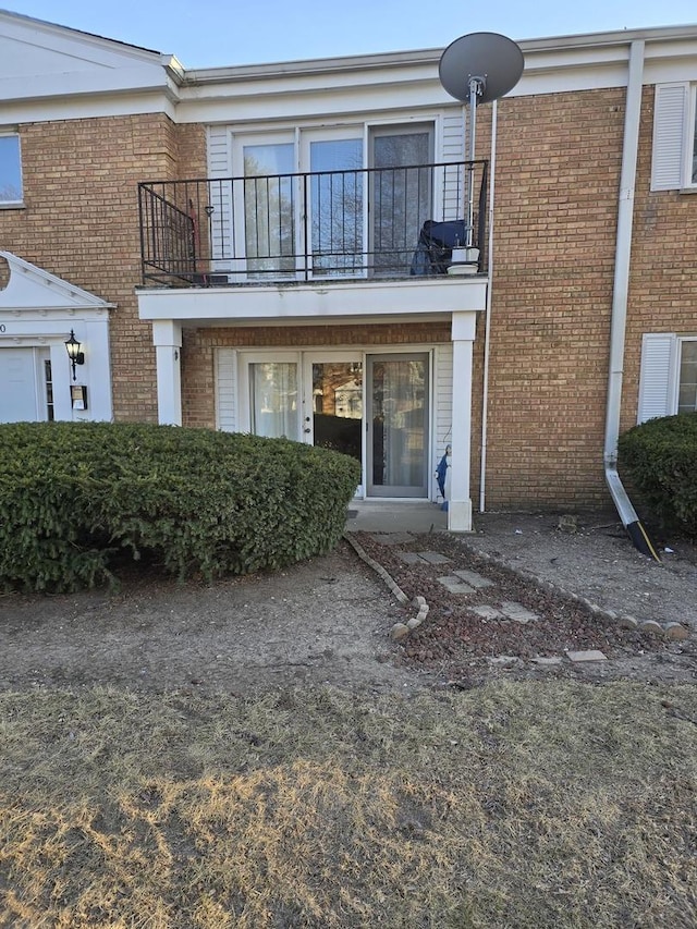 back of house featuring brick siding and a balcony