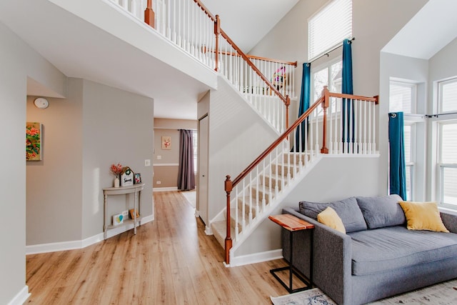 stairs featuring a towering ceiling, baseboards, and wood finished floors