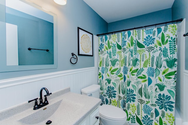 full bath with a wainscoted wall, toilet, and vanity