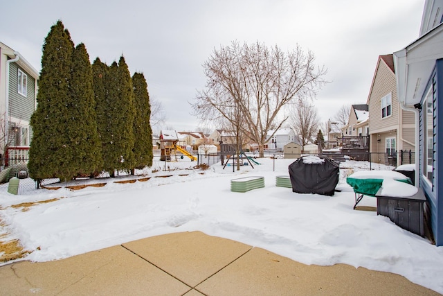 snowy yard featuring a residential view, fence, and a playground