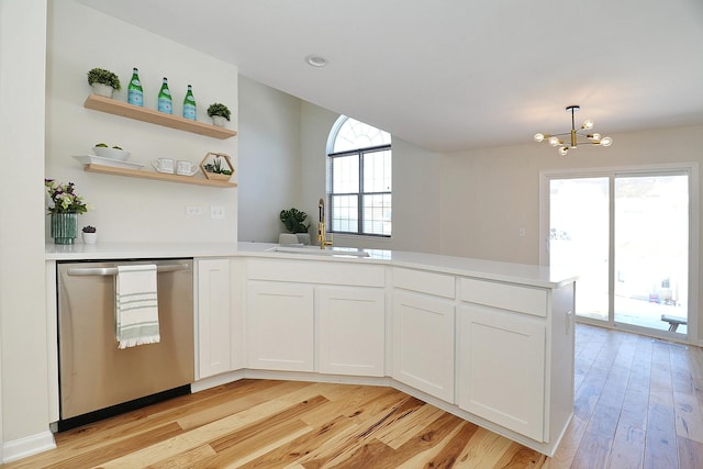 kitchen with a peninsula, a sink, light wood-style floors, light countertops, and stainless steel dishwasher