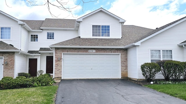 view of front of home with brick siding, driveway, an attached garage, and a shingled roof