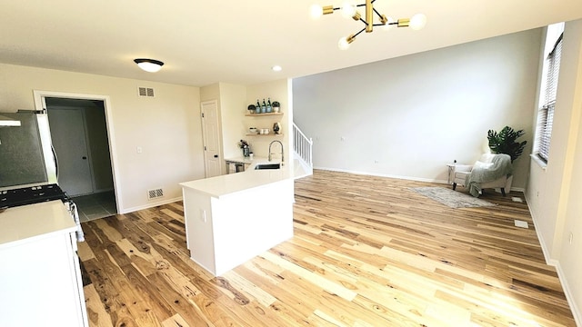 kitchen with visible vents, light countertops, a notable chandelier, and wood finished floors