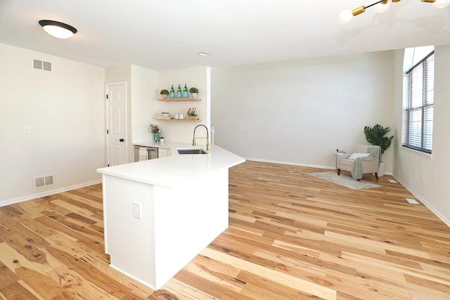 kitchen with light wood-style flooring, a sink, open shelves, and visible vents