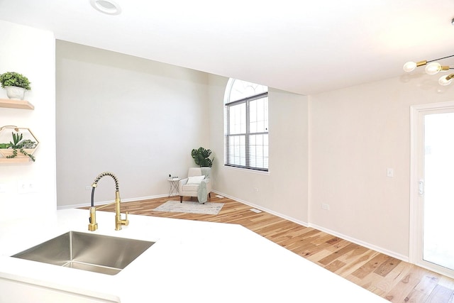 kitchen featuring light wood-style flooring, a sink, open shelves, and baseboards