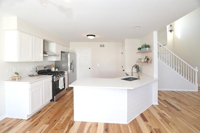 kitchen featuring white cabinets, open shelves, a sink, light wood-type flooring, and appliances with stainless steel finishes
