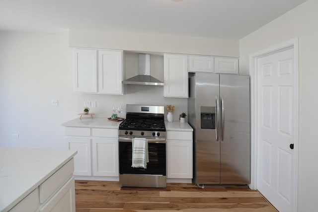 kitchen featuring wall chimney exhaust hood, appliances with stainless steel finishes, white cabinets, and light wood-style floors