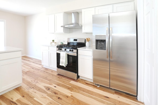 kitchen with wall chimney exhaust hood, light countertops, light wood-style floors, white cabinetry, and stainless steel appliances