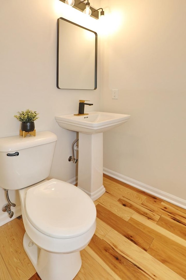 bathroom with toilet, wood finished floors, and baseboards