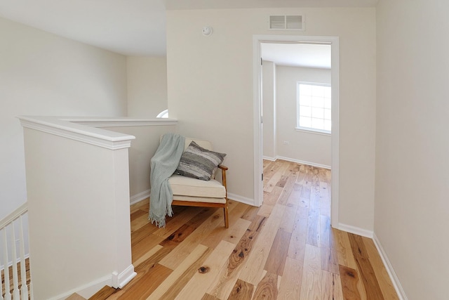 living area with light wood-style flooring, an upstairs landing, visible vents, and baseboards