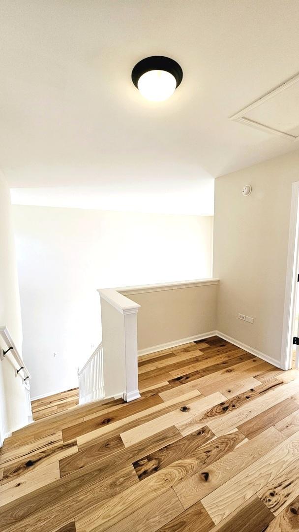 spare room featuring baseboards, attic access, and wood finished floors