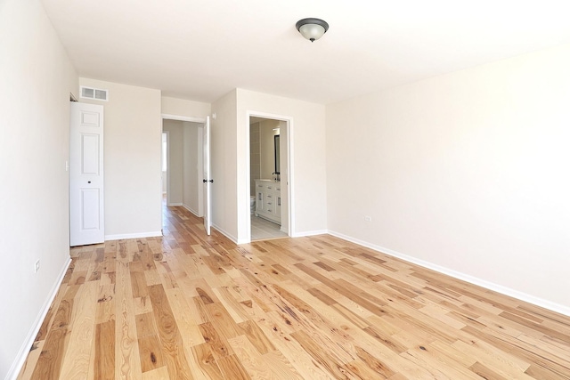unfurnished bedroom featuring light wood-style flooring, ensuite bathroom, baseboards, and visible vents