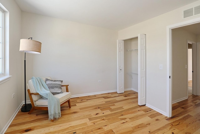 sitting room with light wood finished floors, baseboards, and visible vents