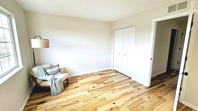 unfurnished room with wood finished floors, baseboards, visible vents, and a wealth of natural light