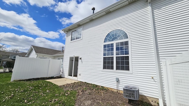 view of side of home featuring central air condition unit, a yard, and fence
