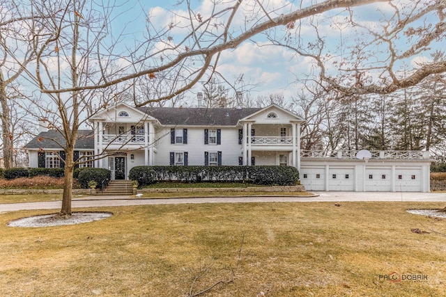 neoclassical / greek revival house featuring a balcony, a detached garage, and a front lawn