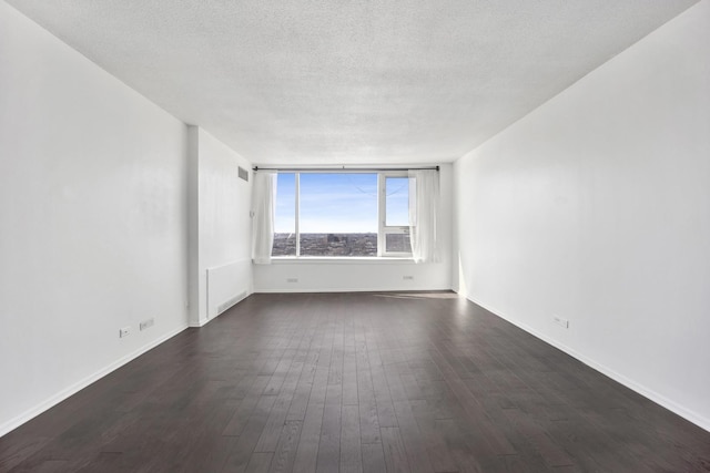 unfurnished room featuring dark wood-style floors, a textured ceiling, and baseboards