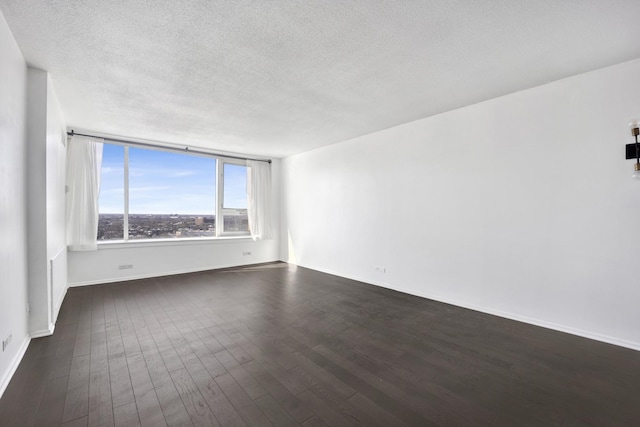 spare room featuring dark wood-style floors, baseboards, and a textured ceiling